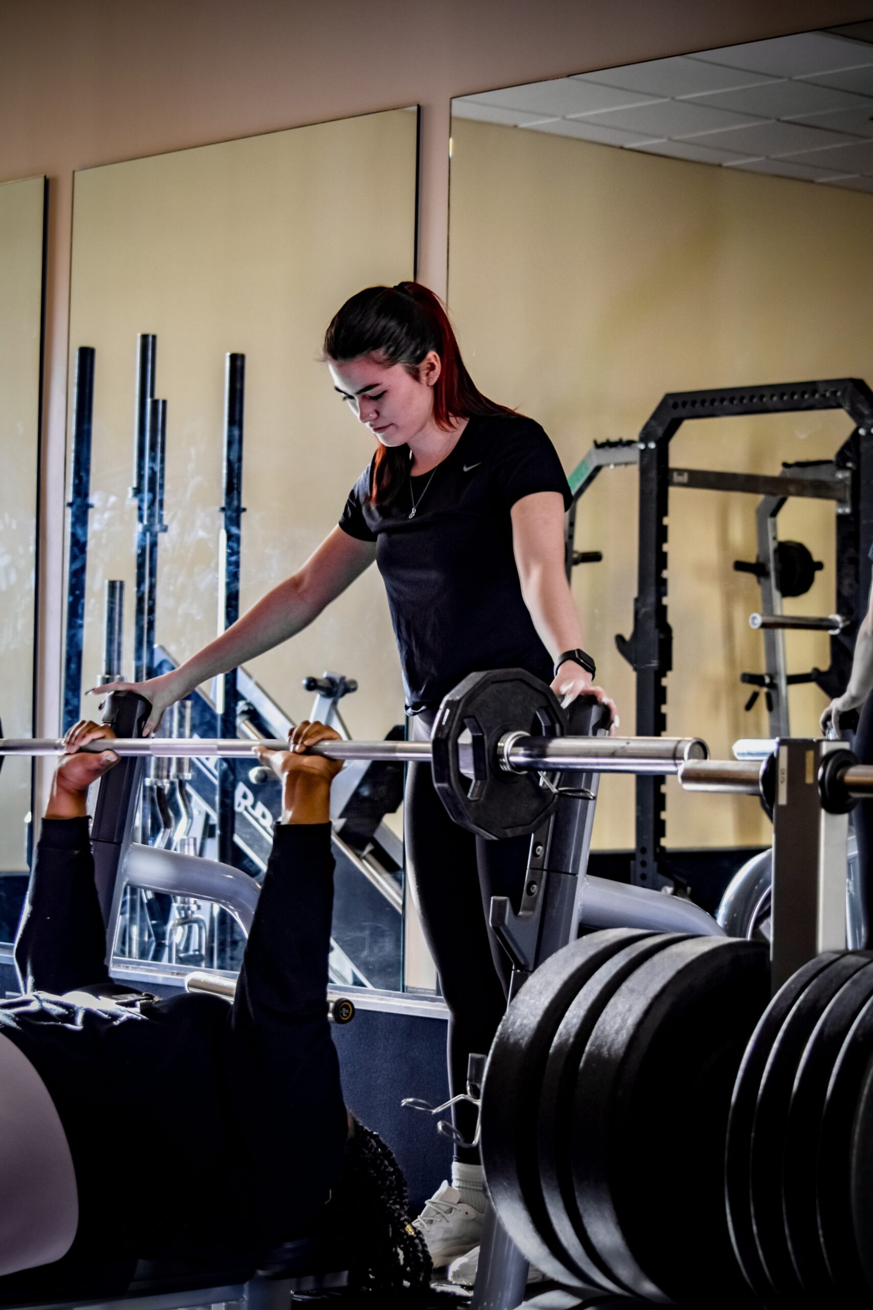 A female trainer teaching weight lifting techniques to the female client.